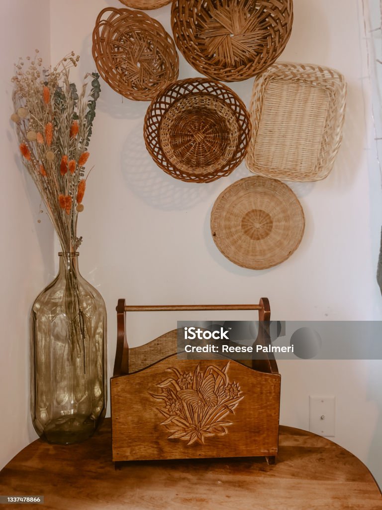 Wicker bowls and old wooden crate close up Wicker Bowles and baskets on the wall along with dried flowers and a old small crate. This style can really calm down and bring a safe feeling to a room while still being trendy. Really shows how to be modern on a thrifty budget Color Image Stock Photo