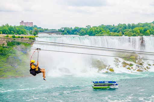 Woman going down zipline in front of Niagara Falls during summer day