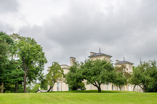 Facade of Dundurn Castle seen though trees in Hamilton during summer day