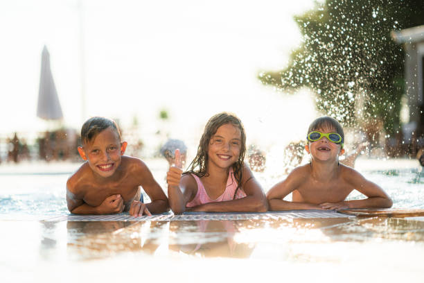 istock Playful kids having fun while splashing water in the swimming pool 1337480154