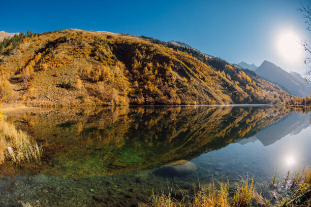 istock Mountain lake with reflection, autumnal trees and mountains with sun. 1337483482