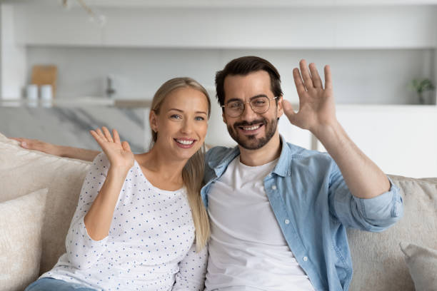 istock Happy millennial couple waving hello, smiling at webcam 1337484881