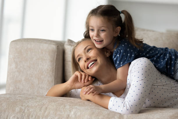 istock Laughing mom and daughter kid resting on couch at home 1337484887