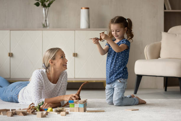 istock Happy mom and daughter playing with dinosaurs on warm floor, 1337484898