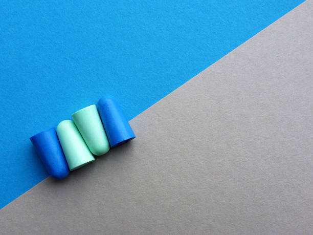 istock Green and blue earplugs on blue and gray background 1337485875
