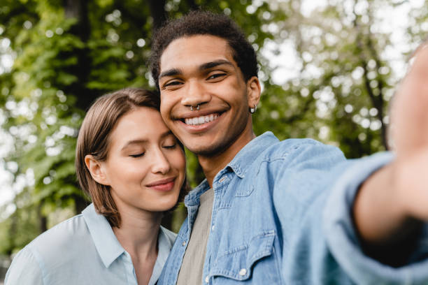 istock Cheerful happy young romantic couple spending time together on romantic date taking selfie on smartphone in city park. Friends boyfriend and girlfriend students taking photo outdoors. 1337486880
