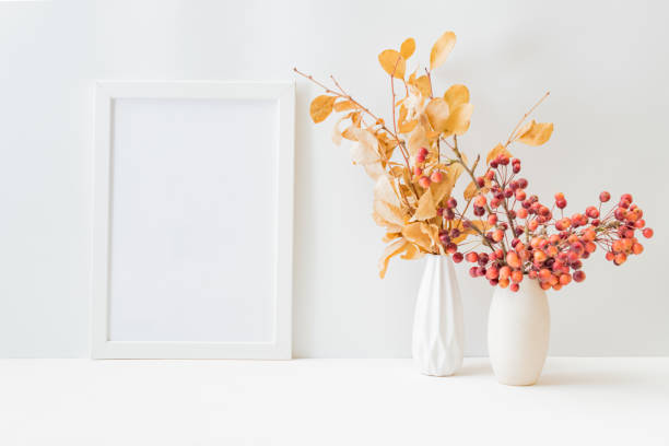 istock Home interior with decor elements. Mockup with a white frame, dry autumn leaves in a vase on a light background 1337488235