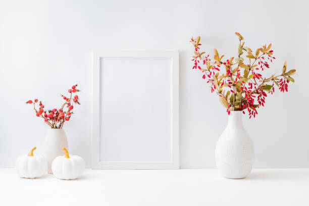 istock Home interior with decor elements. Mockup with a white frame, colorful autumn leaves and red berries in a vase on a light background 1337488273
