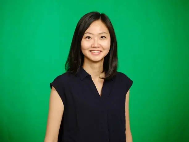A studio portrait of a Japanese ethnicity woman, against a green background.