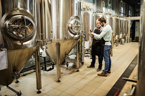 Senior and his son in a family brewery checking quality together Senior and his son in a family brewery checking quality brewery stock pictures, royalty-free photos & images