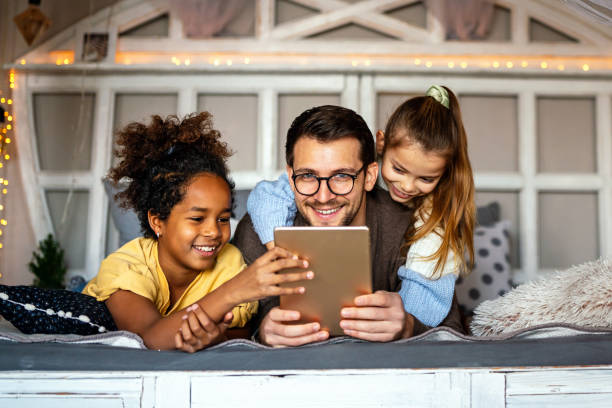 istock Multiethnic children and father having fun, playing on tablet at home 1337494560