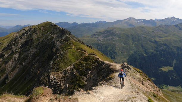 istock Mountain biker follows trail down sunny mountain ridge 1337494587