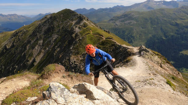 istock Mountain biker climbs trail up sunny mountain ridge 1337494663