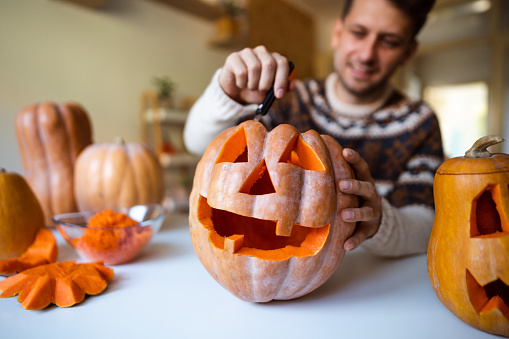 Hombre guapo tallando una calabaza para Halloween en casa photo