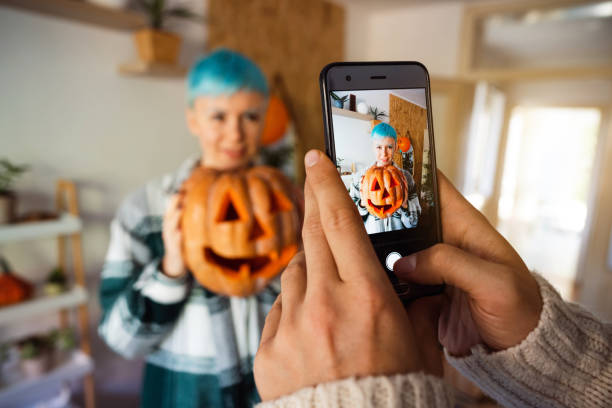 istock Young couple capturing moments with smart phone while preparing pumpkins for Halloween 1337495990