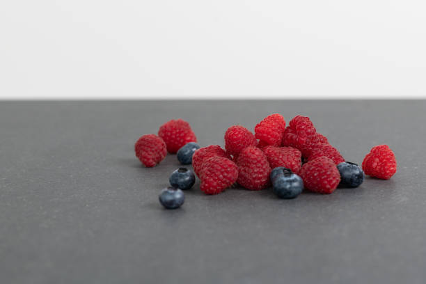 A mixture of raspberries and blueberries against a white background