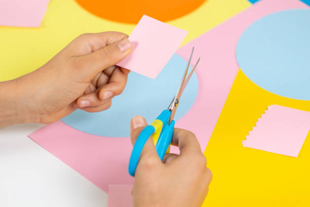 istock Hands cuting colored paper with scissors. Education, learning, paper craft, entertainment at home 1337505241