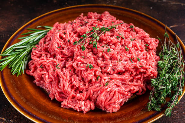 istock Raw ground beef or veal meat on a rustic plate with herbs. Dark background. Top view 1337511115
