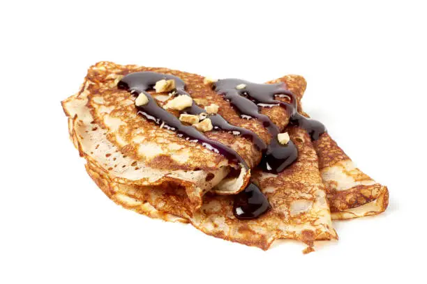 Stack of folded crepes with chocolate sauce isolated on white