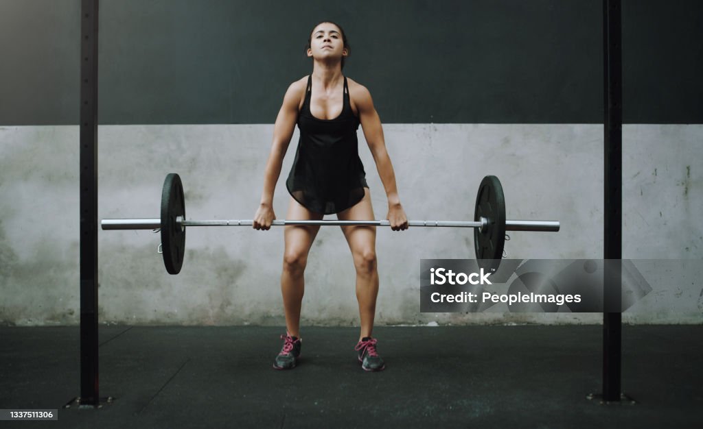 Shot of a young woman exercising with a barbell in a gym With a little effort you can build ultimate power Barbell Stock Photo