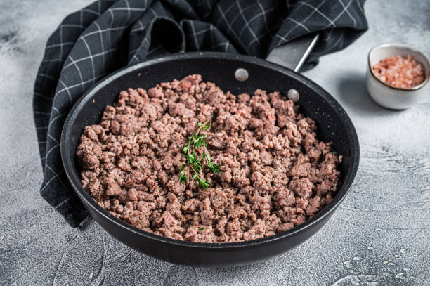istock Fried ground mince beef and pork meat in a pan with herbs. White background. Top view 1337512362