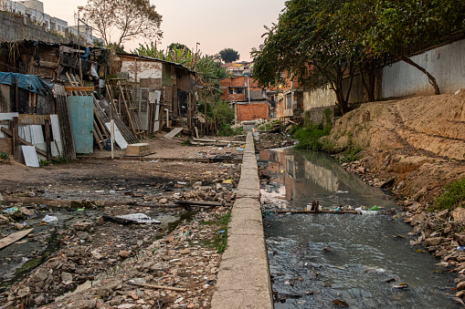 Sewage running alongside wooden shacks in a slum