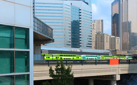 Toronto, Ontario, Canada-June 2, 2021: Toronto Go Train arriving at a platform at Union station terminal while passing CN Tower and urban skyline buildings