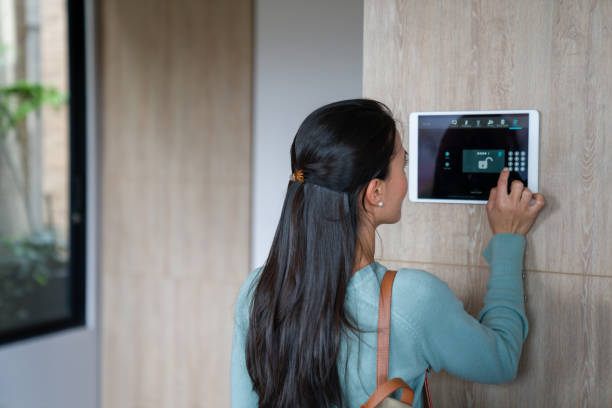 mujer que ingresa pin para cerrar la puerta de su casa utilizando un sistema de domótica - alarma de seguridad fotografías e imágenes de stock