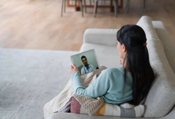 Photo of Woman at home feeling poorly and talking to her doctor on a video call
