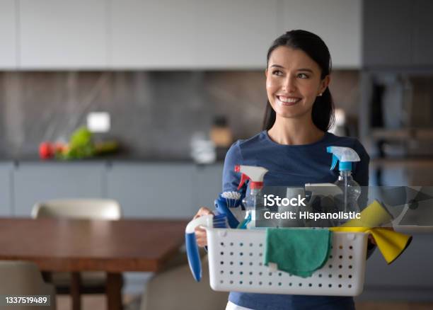 Happy Woman At Home Holding A Basket Of Cleaning Products Stock Photo - Download Image Now