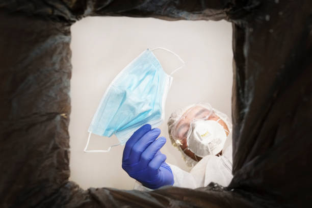 istock man in a protective suit throws used medical mask into a trash can. Bottom view from the trash can. The problem of recycling and pollution of the planet with garbage. 1337522604