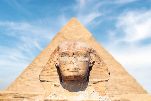 la gran esfinge es el monumento más antiguo de giza, egipto. la cabeza de la esfinge es precisamente simétrica contra el fondo de la pirámide de kefrén. fondo en un hermoso cielo azul nublado - la esfinge fotografías e imágenes de stock