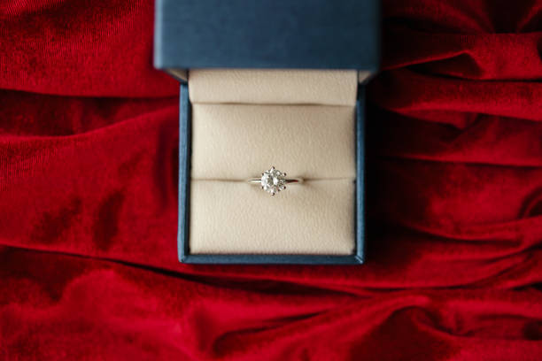 istock Diamond ring in jewelry gift box on red fabric background 1337522894