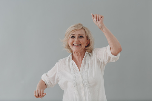 Elderly caucasian old aged woman dancing party celebration on gray background. Old people positive mental state concept