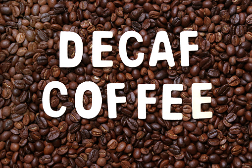 Palabra de café descafeinado en el fondo de granos de café tostados. photo