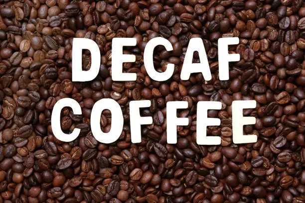 Photo of Decaf coffee word on roasted coffee beans background.