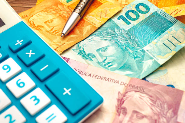 Real - money from Brazil. Brazilian Real banknotes on a wooden table with a calculator and pen in the composition. economics and financial planning Real - money from Brazil. Brazilian Real banknotes on a wooden table with a calculator and pen in the composition. economics and financial planning brazilian currency photos stock pictures, royalty-free photos & images