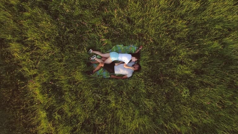 The attractive man and woman laying on green grass