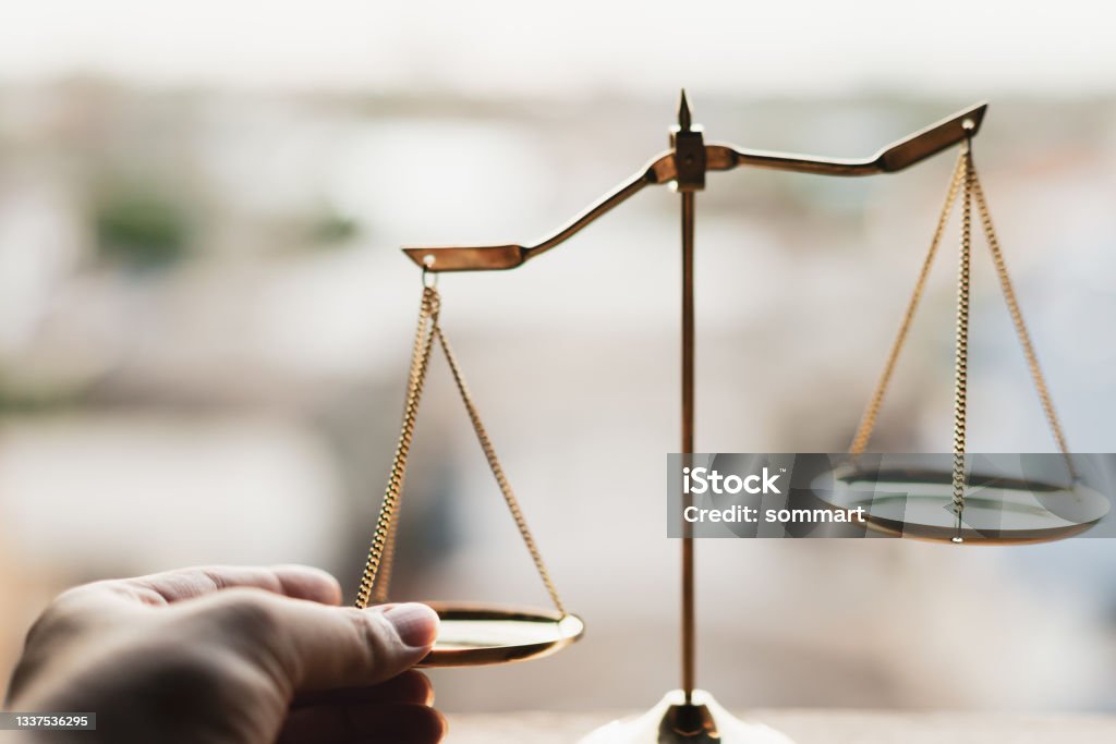 Tip the scales of justice concept as a the hand of a person illegaly influencing the legal system for an unfair advantage. Domination Stock Photo