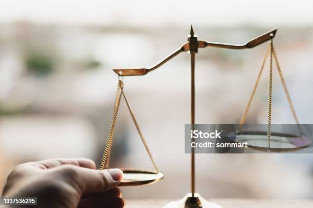 Tip The Scales Of Justice Concept As A The Hand Of A Person Illegaly Influencing The Legal System For An Unfair Advantage Stock Photo - Download Image Now