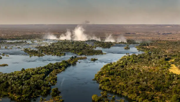 landscape  view down the Zambezi river to Victoria falls - rising spray from the fall in the background