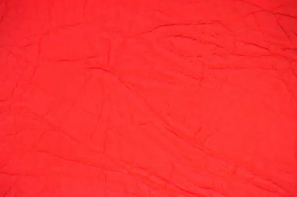 Photo of Genuine leather with wrinkles and folds, dyed in bright red.