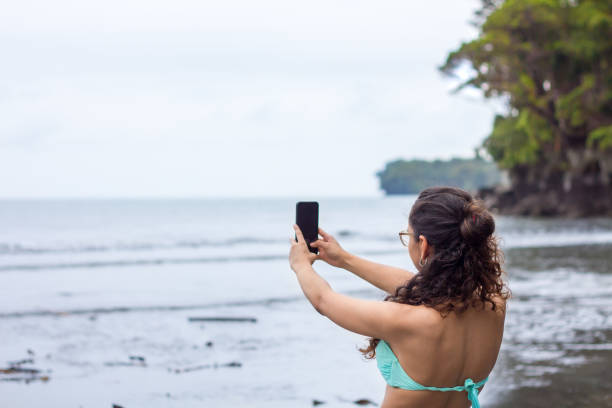 istock Girl using a cell phone at the beach and using an app 1337541246