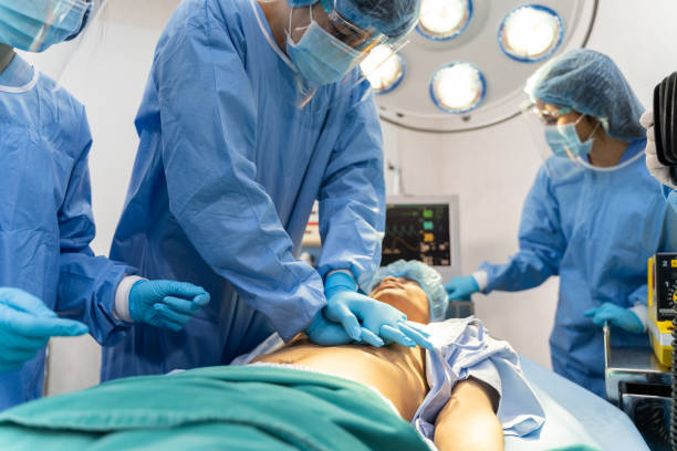 el equipo médico en bata quirúrgica ayuda al paciente a realizar rcp cardio reanimación pulmonar en el quirófano del hospital - surgery emergency room hospital operating room fotografías e imágenes de stock