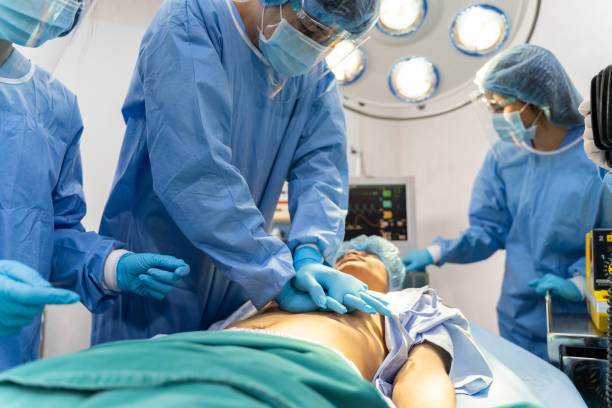 zespół medyczny w fartuchu chirurgicznym pomaga pacjentowi w wykonaniu resuscytacji krążeniowo-oddechowej w sali operacyjnej w szpitalu - surgery emergency room hospital operating room zdjęcia i obrazy z banku zdjęć