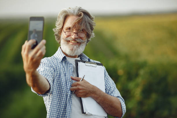 istock Old farmer in shirt standing on field with notebook 1337555980