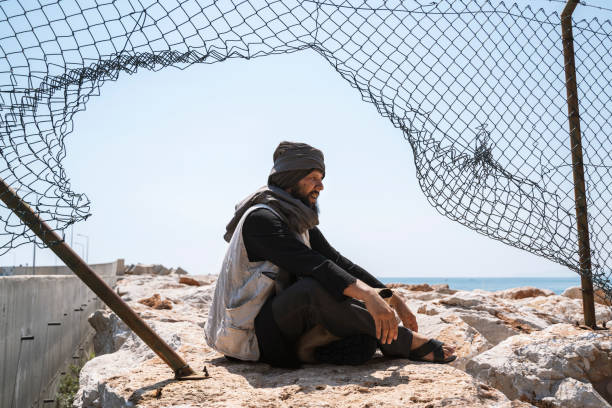 istock Refugee man sitting behind the fence 1337559045