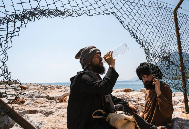 istock Two male refugee men sitting under the fence 1337559046