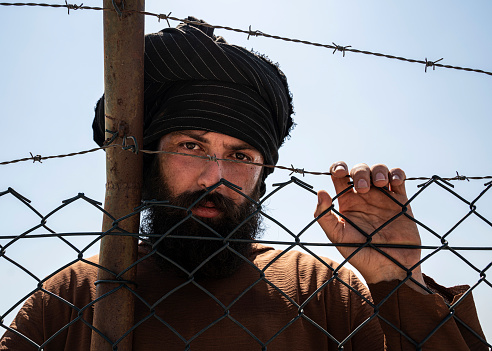 Hombre refugiado de pie detrás de la valla photo