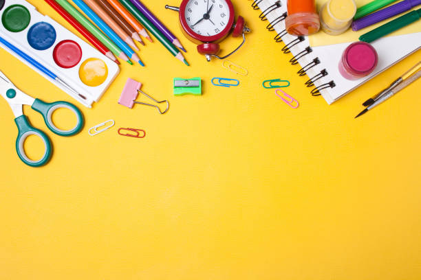 istock Alarm clock, paint, pencils and scissors. School accessories on a yellow background. View from above 1337567985